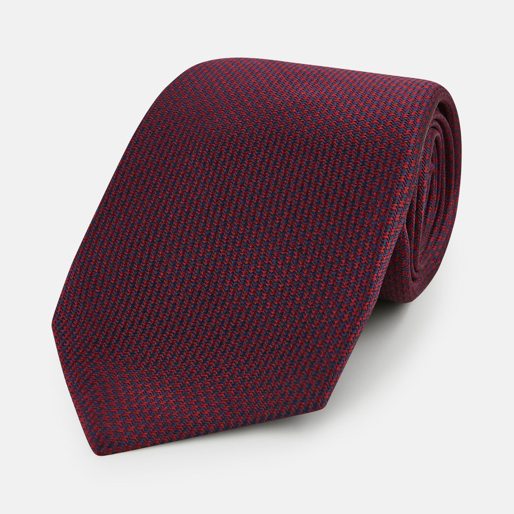 A close-up of the Turnbull & Asser UK Seven-Fold Navy and Red Silk Tie, featuring a small textured check pattern reminiscent of houndstooth, displayed on a plain white background.