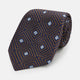 The Tomorrow Never Dies Seven-Fold Silk Tie by Turnbull & Asser UK features a geometric pattern of navy and brown squares with light blue diamond accents, rolled up and displayed on a plain white background.