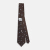 View 3 of product The Turnbull & Asser UK Tomorrow Never Dies Seven-Fold Silk Tie, as seen on James Bond, features a navy blue and brown geometric diamond pattern with silver squares at the center, set on a light background.