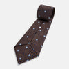 View 5 of product The Tomorrow Never Dies Seven-Fold Silk Tie by Turnbull & Asser UK features a geometric pattern of navy and brown squares with light blue diamond accents, rolled up and displayed on a plain white background.