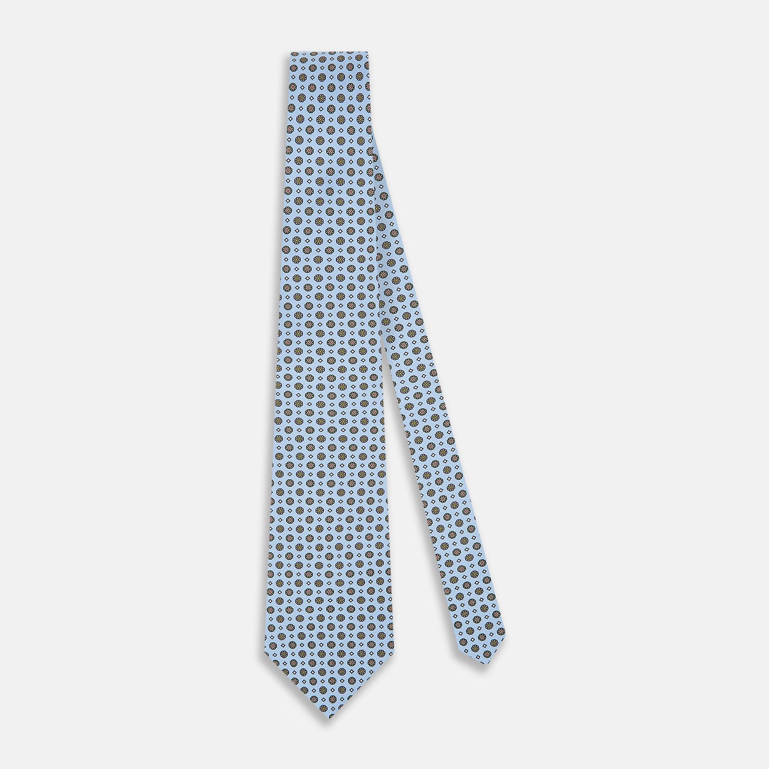 View 2 of product The Turnbull & Asser UK Great Gatsby Seven-Fold Silk Sky Tie, as seen on Jay Gatsby, is a light blue silk tie with a repeating floral medallion pattern in black, yellow, and red circles, shown rolled on a white background.