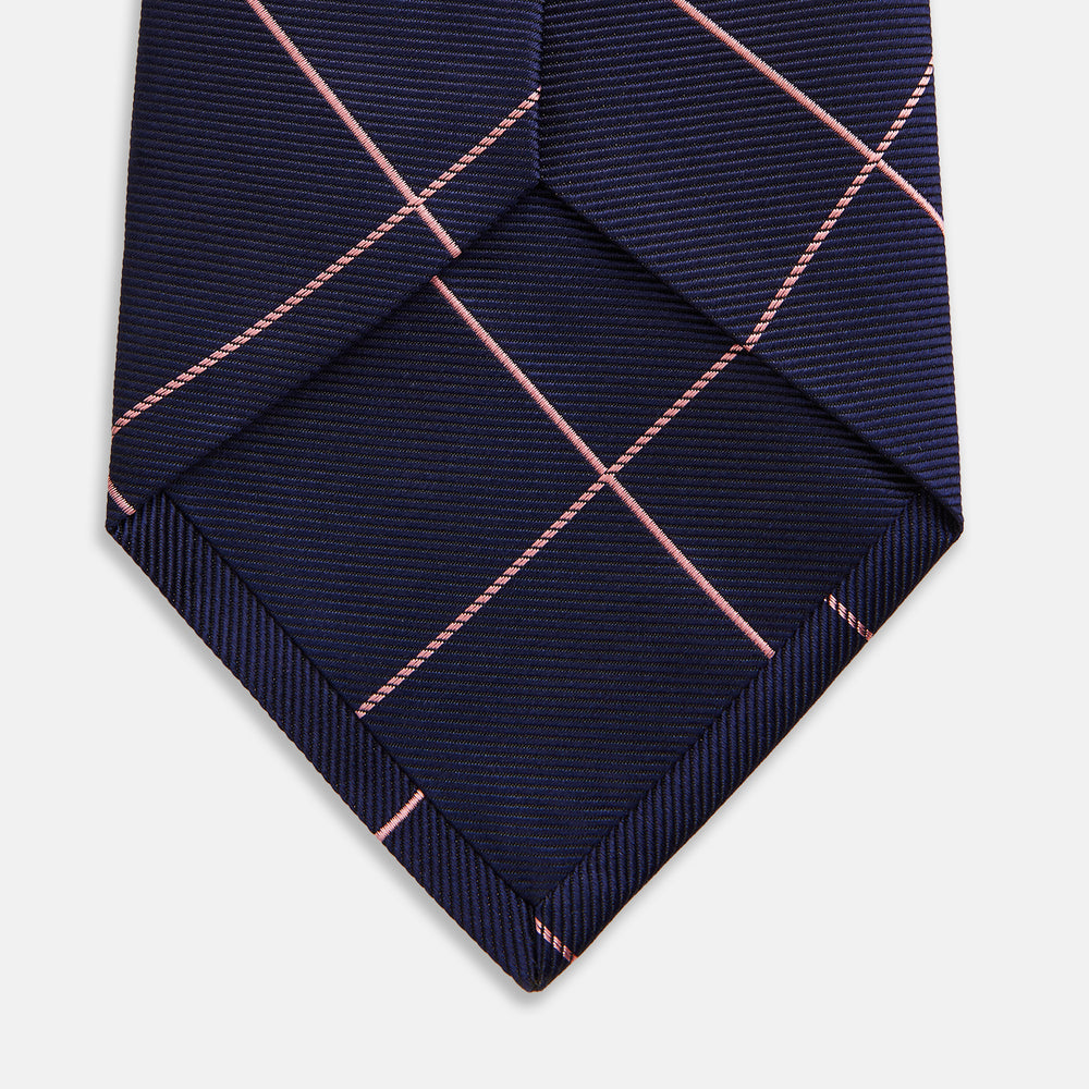 The Turnbull & Asser FONDANT PINK and WINDOW PANE NAVY Silk Tie features a subtle ribbed texture with a pink grid pattern on navy—an elegant choice for polished office attire, shown neatly rolled on a white background.