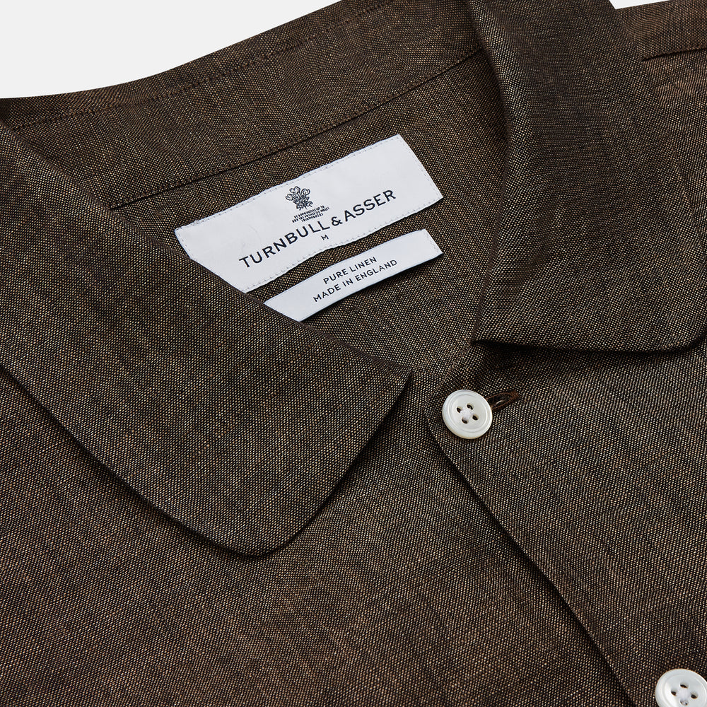 The Turnbull & Asser Chocolate Brown Linen Holiday Fit Fellows Shirt, featuring long sleeves, a classic collar, and white buttons, is displayed flat on a white background—ideal for effortless summer style.