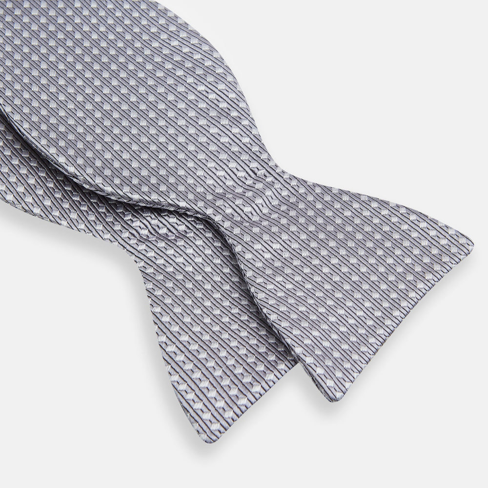 The Turnbull & Asser Silver and White Square Silk Bow Tie features a subtle geometric pattern, ideal for formalwear, and is displayed against a plain white background.