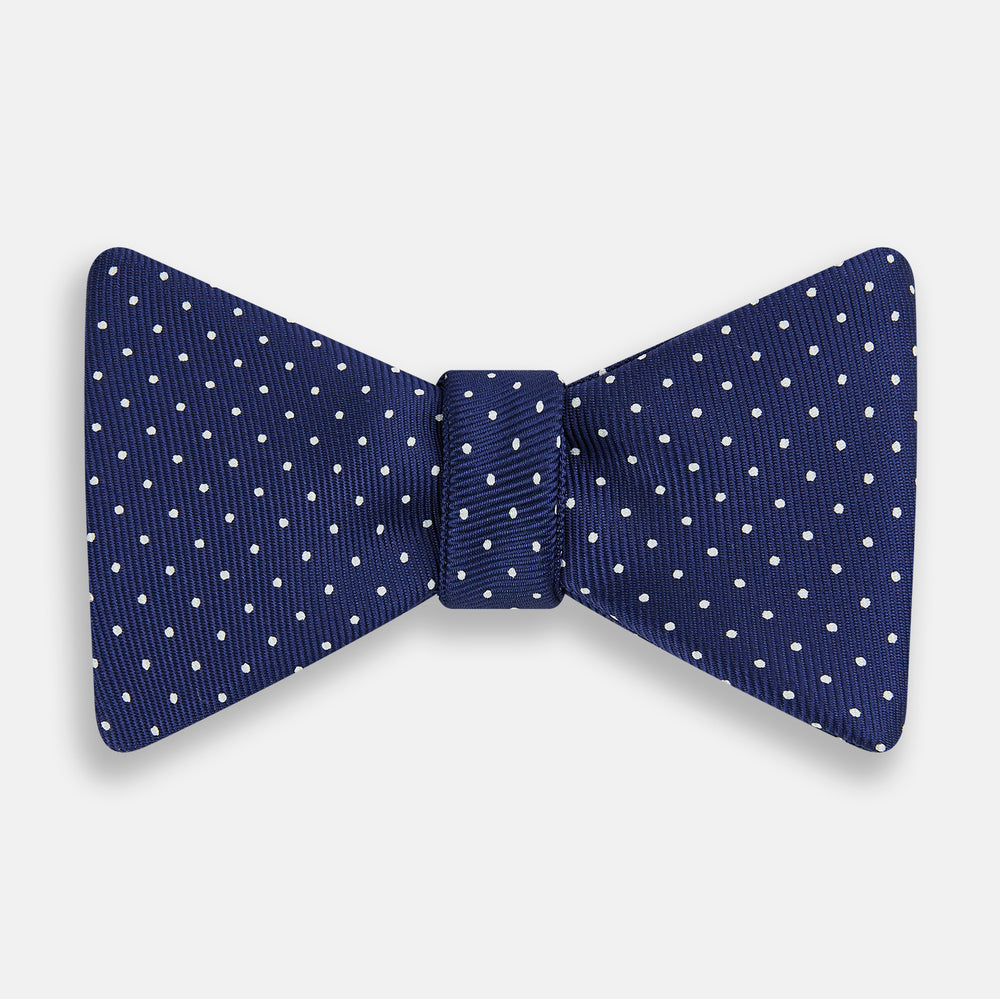 The Turnbull & Asser Azzurro and White Spot Silk Bow Tie features a classic blue silk design with small white spots, shown elegantly against a plain white background.