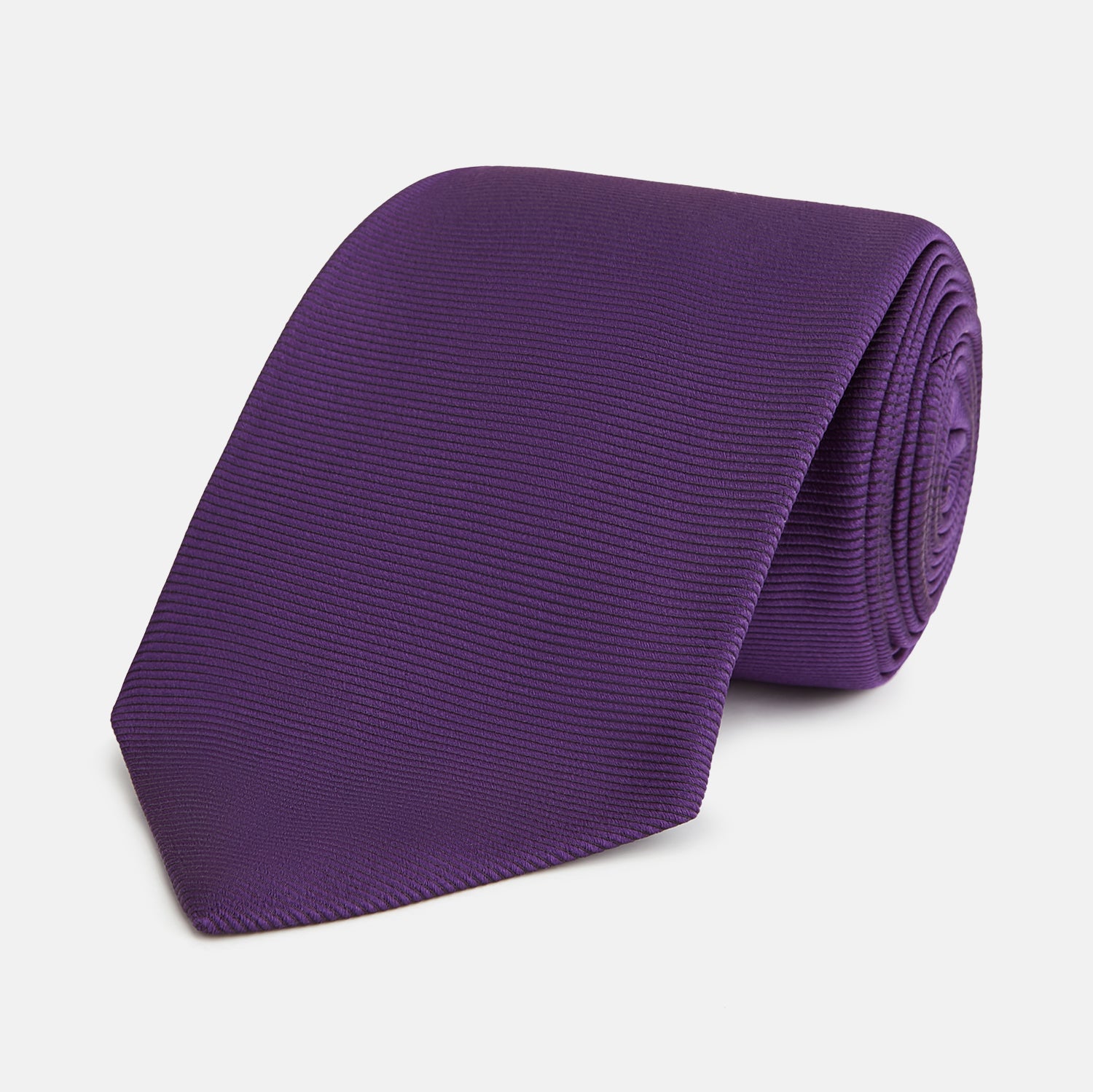 View 1 of product The HORIZONTAL TWILL PLUM TIE by Turnbull & Asser features a solid purple hue and smooth, subtly textured fabric—a versatile accessory to elevate any wardrobe, shown elegantly against a white background.