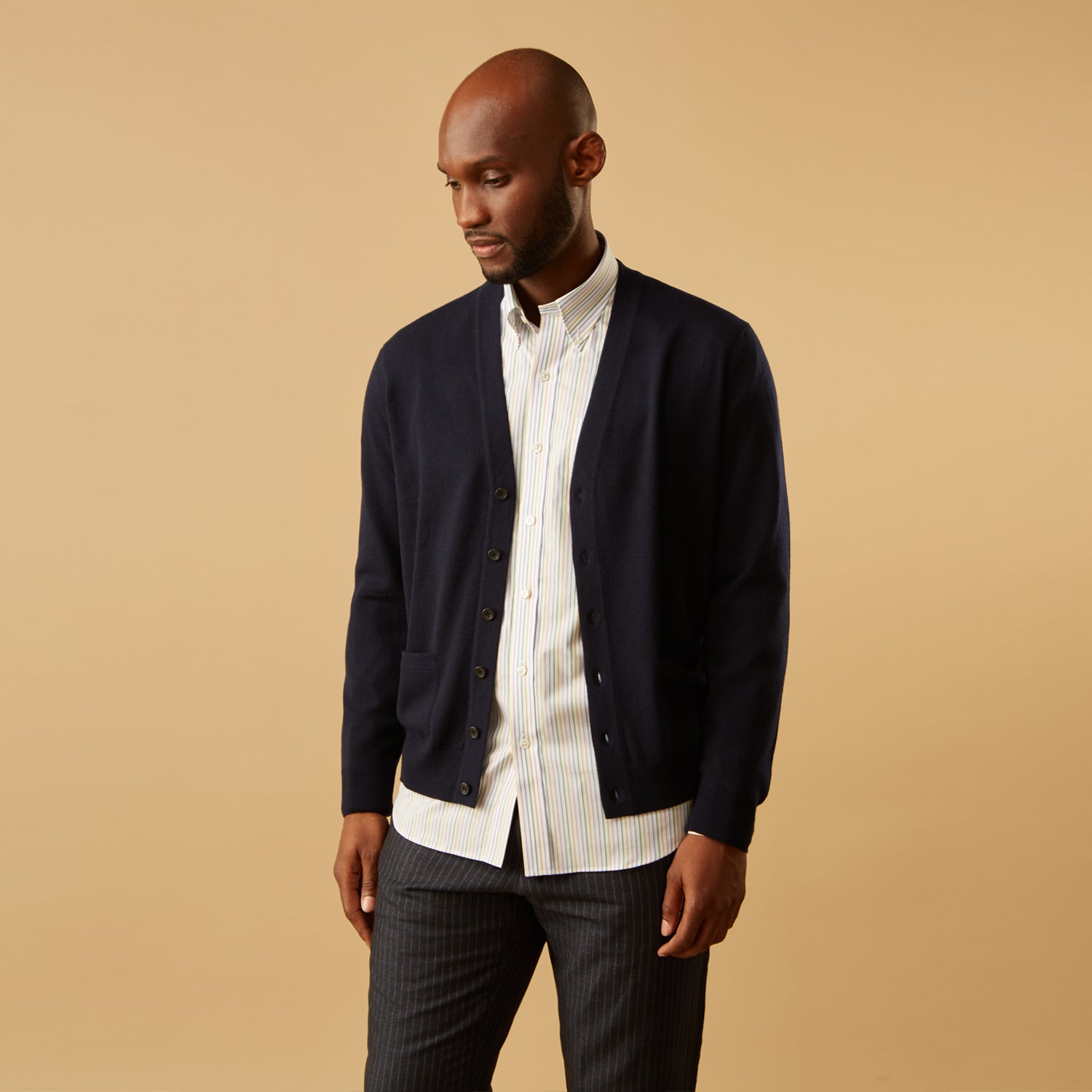 View 5 of product A man wears the Turnbull & Asser Yellow Multi Blazer Stripe Weekend Fit Suffolk Shirt, standing against a beige background with his hands relaxed—a casual look perfect for weekends.