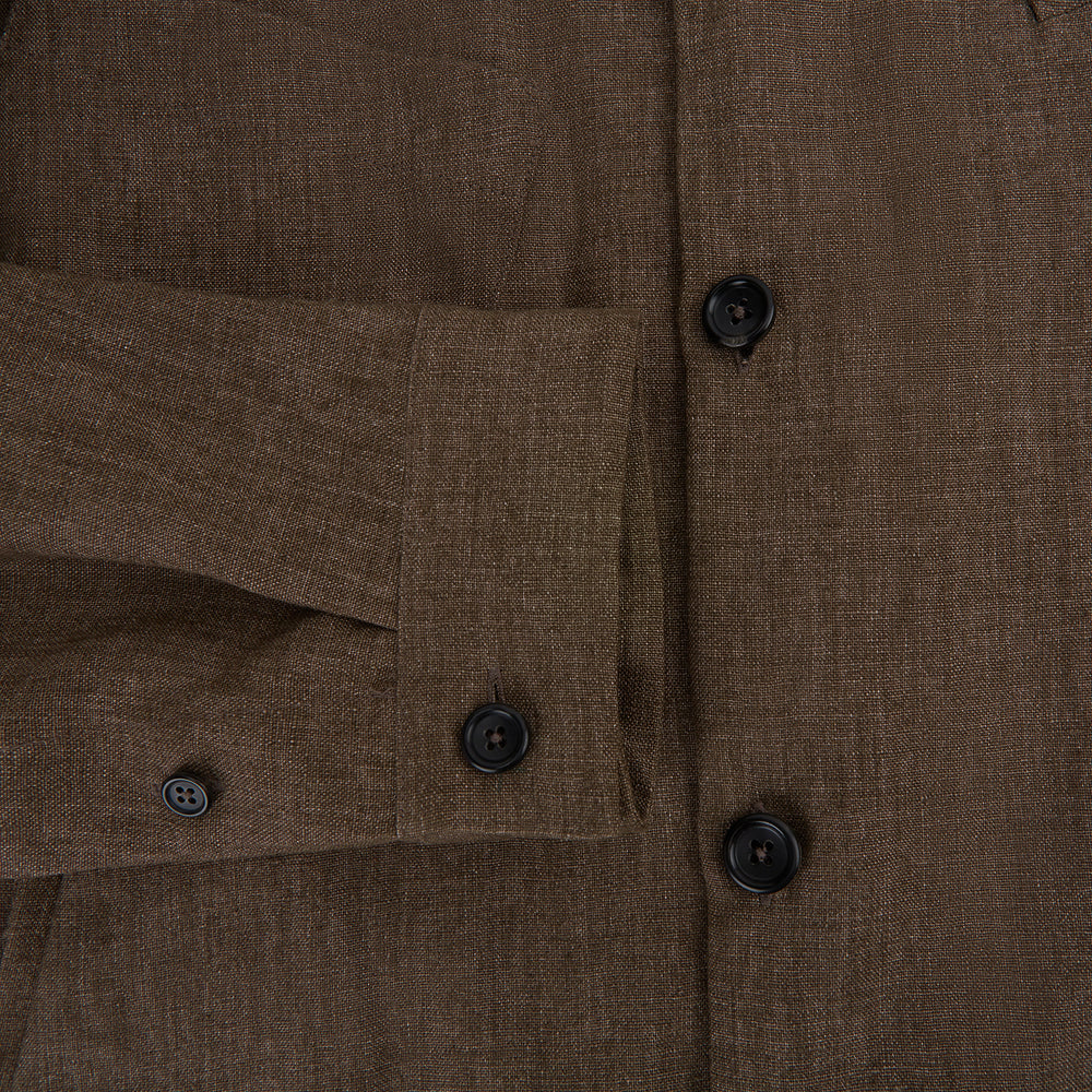 The Pine Cone Linen Holland Shacket by Turnbull & Asser is a brown men's lightweight outerwear piece with a collar, long sleeves, three front zip pockets, and black buttons, shown on a white background.