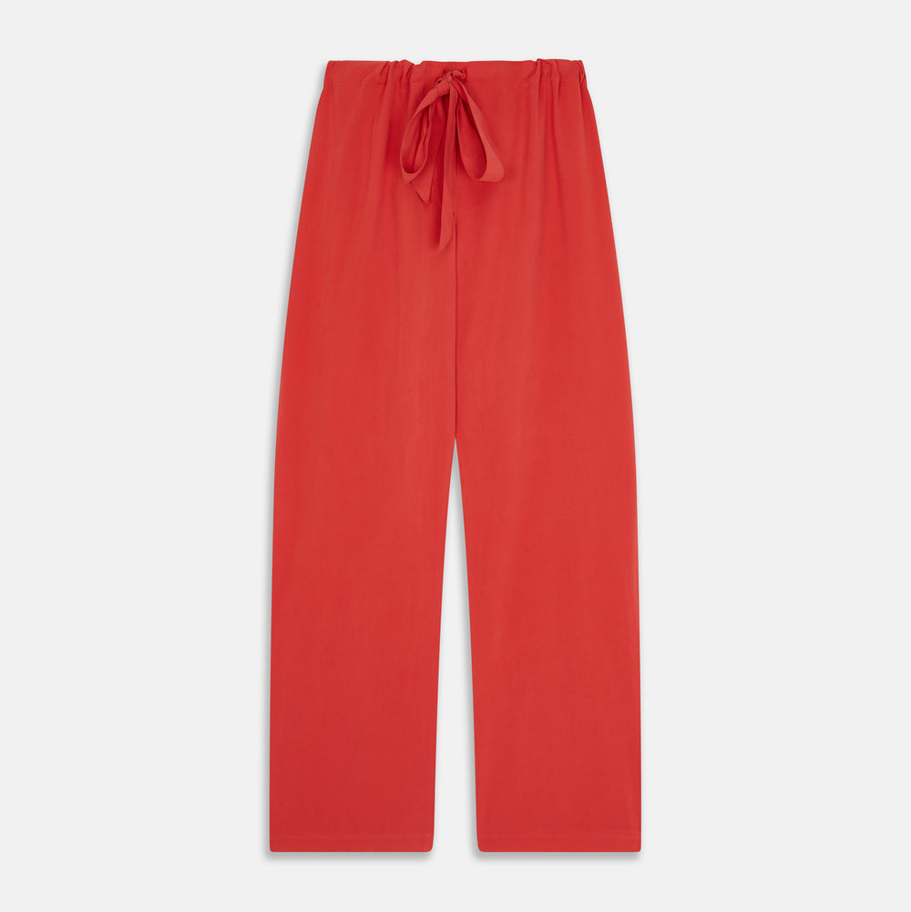 The Turnbull & Asser Women's Coral Pink Silk Thelma Pyjama Set features a long-sleeve button-up top with two front pockets and matching drawstring pants, shown on a white background.