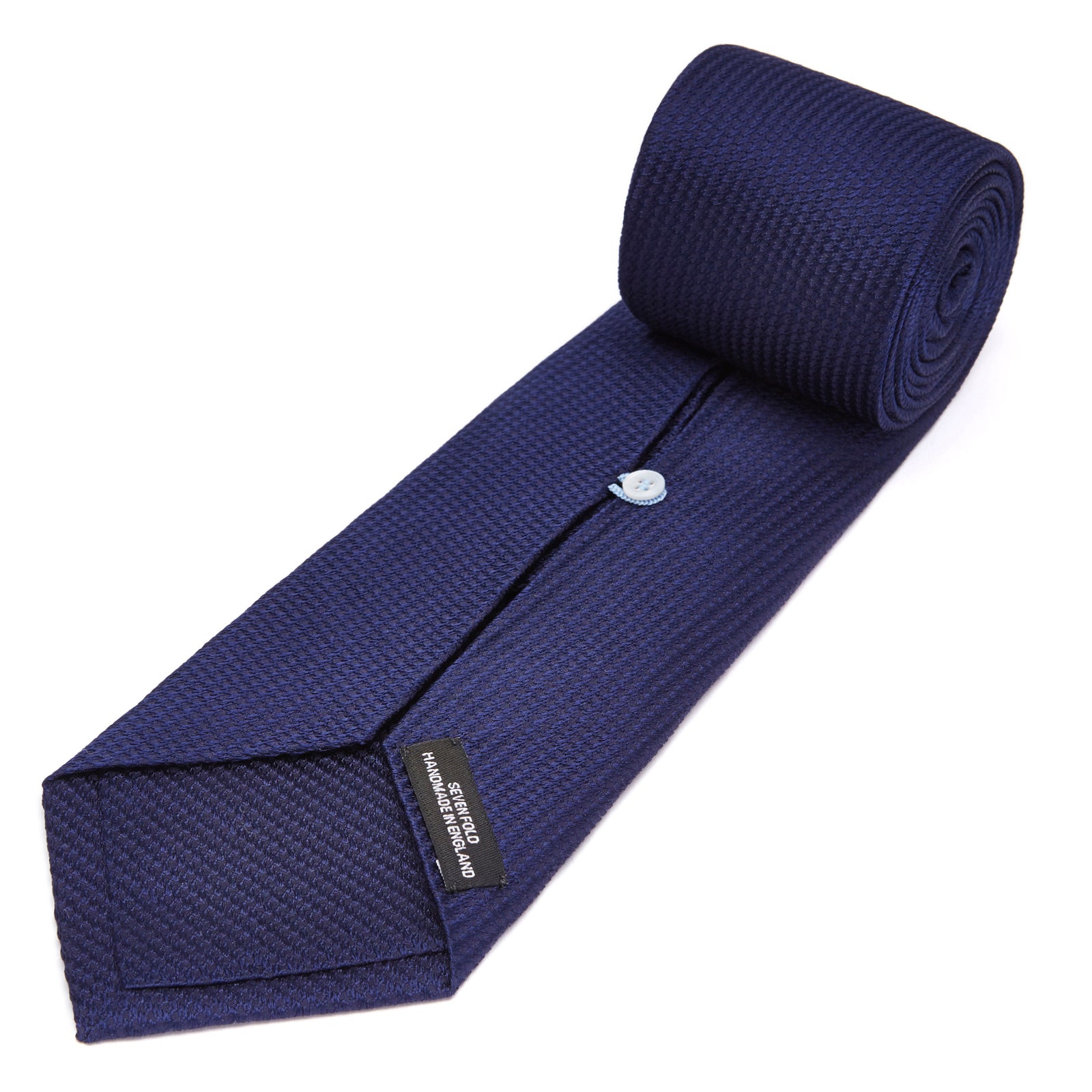 View 4 of product The Turnbull & Asser Seven-Fold Navy Lace Silk Tie is shown on a white background, rolled at one end with the pointed tip facing forward.