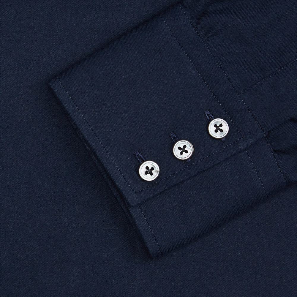 The Turnbull & Asser Navy Cotton Regular Fit Mayfair Shirt is a long-sleeved men’s formal shirt with a collar and white buttons, shown against a plain white background.