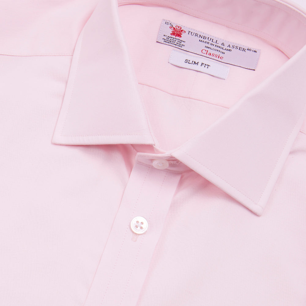 The Turnbull & Asser Pink Poplin Slim Fit Regent Collar Shirt features white buttons and a slim fit label, neatly folded and displayed on a plain white background.