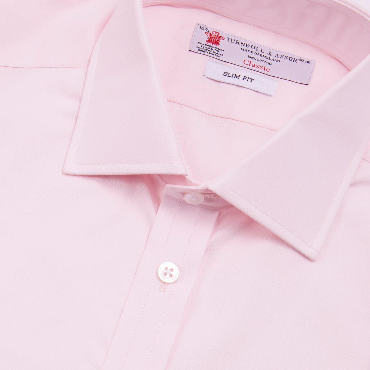 View 4 of product The Turnbull & Asser Pink Poplin Slim Fit Regent Collar Shirt features white buttons and a slim fit label, neatly folded and displayed on a plain white background.