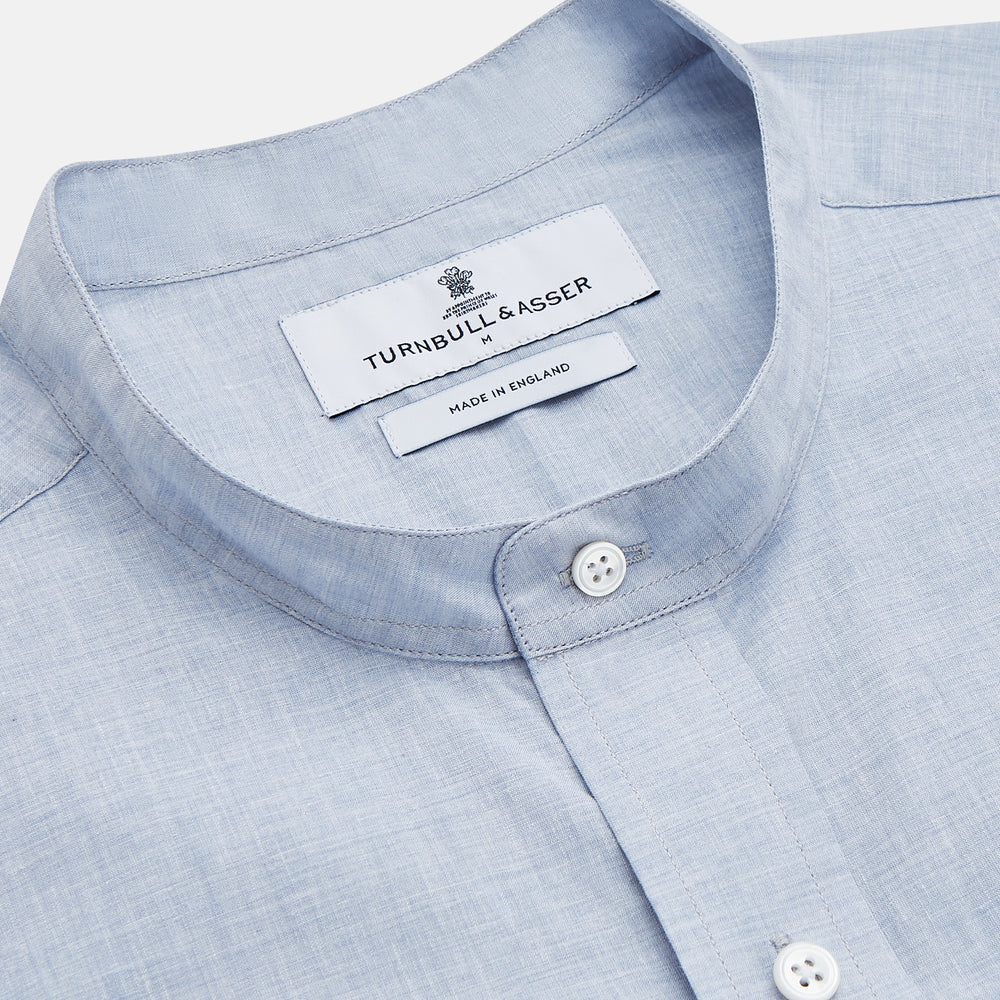 Turnbull & Asser’s Pale Blue Linen Blend Weekend Fit Unwin Shirt features long sleeves, a band collar, two chest pockets, and white buttons—ideal for casual summer wear.
