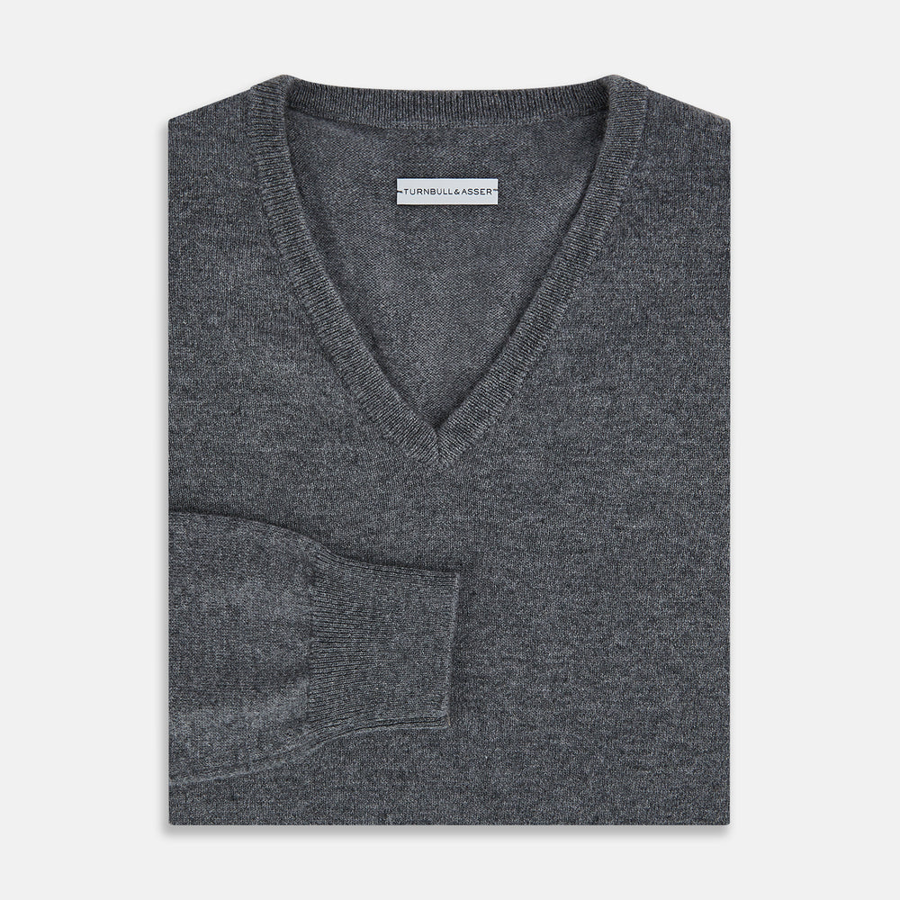 The Turnbull & Asser Storm Grey Cashmere V-neck Jumper features long sleeves, ribbed cuffs and hem—versatile knitwear shown on a white backdrop.