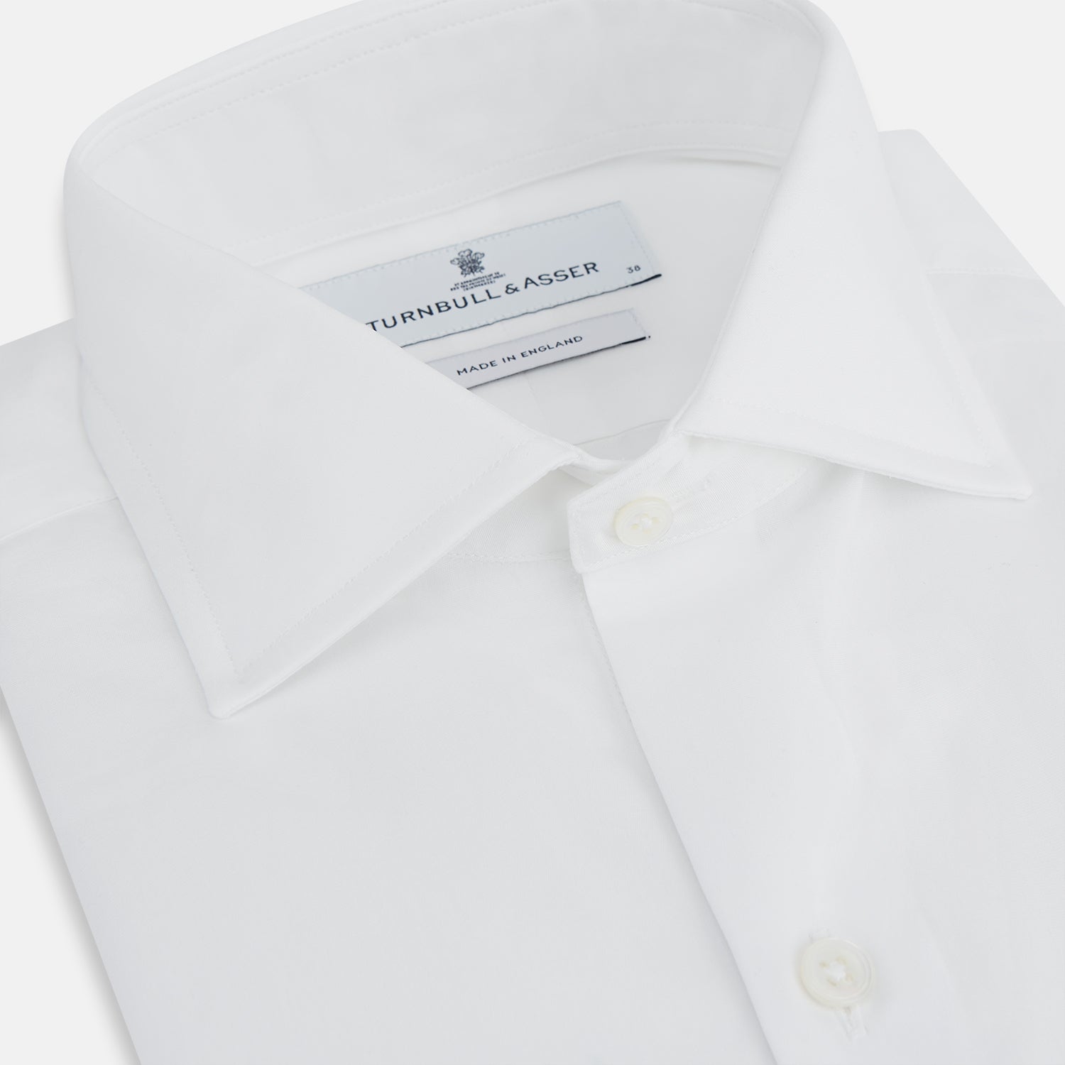View 2 of product The Turnbull & Asser Tailored Fit Plain White Cotton Shirt features a Kent collar, button-down front, long sleeves, and double cuffs, shown on a white background.
