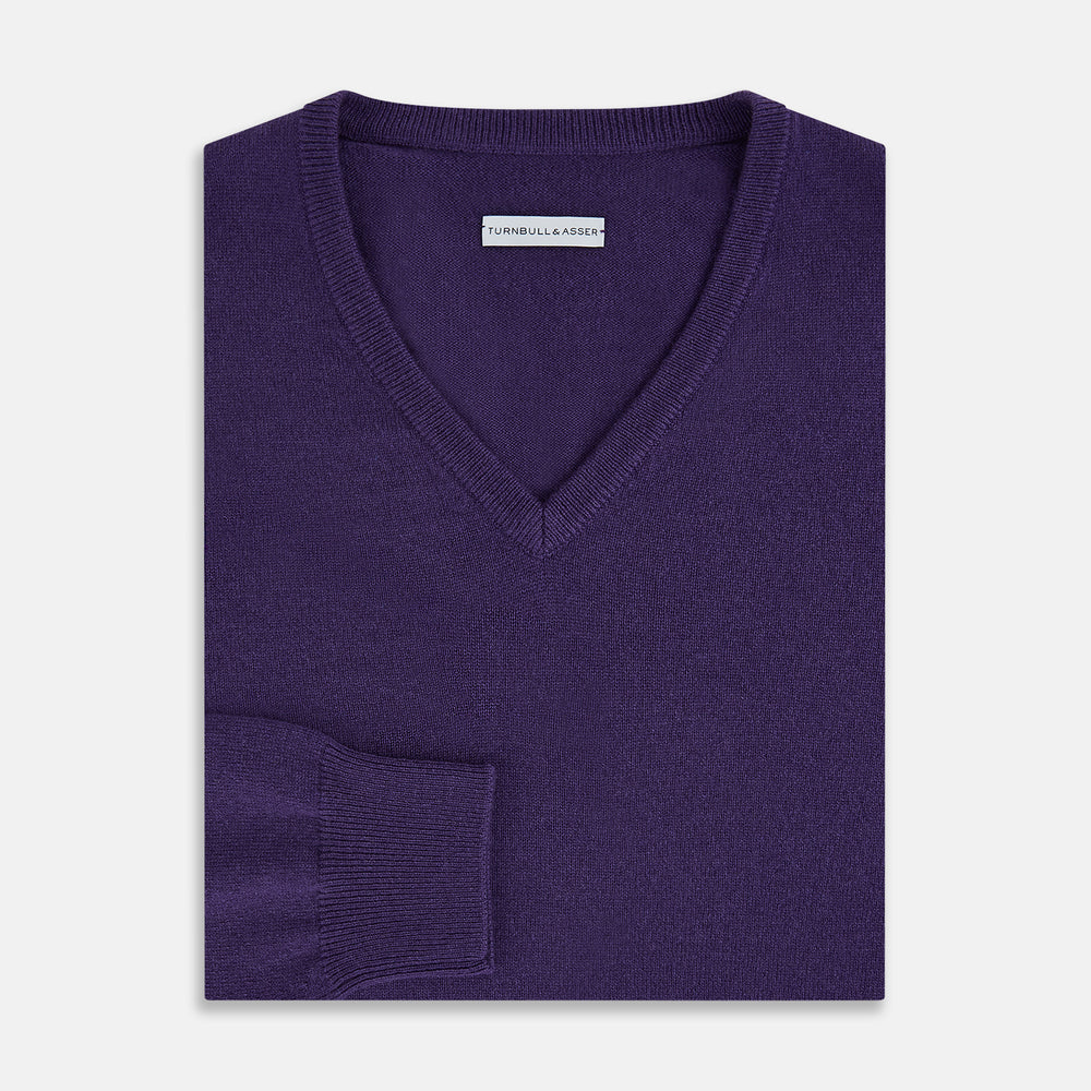 The Turnbull & Asser Purple Cashmere V-neck Jumper features long sleeves with ribbed cuffs and hem—a classic knitwear piece for effortless layering, shown against a white background.
