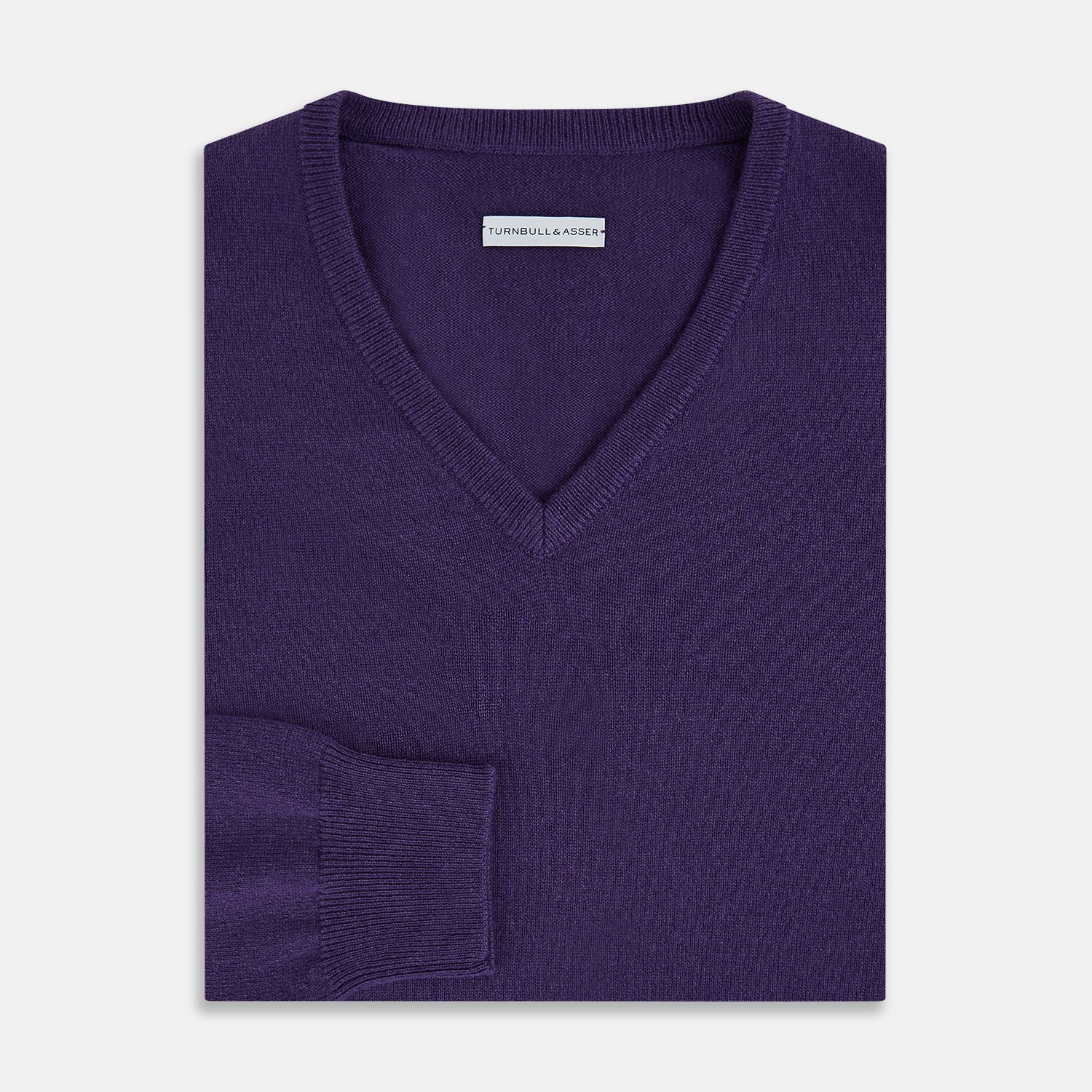 View 4 of product The Turnbull & Asser Purple Cashmere V-neck Jumper features long sleeves with ribbed cuffs and hem—a classic knitwear piece for effortless layering, shown against a white background.