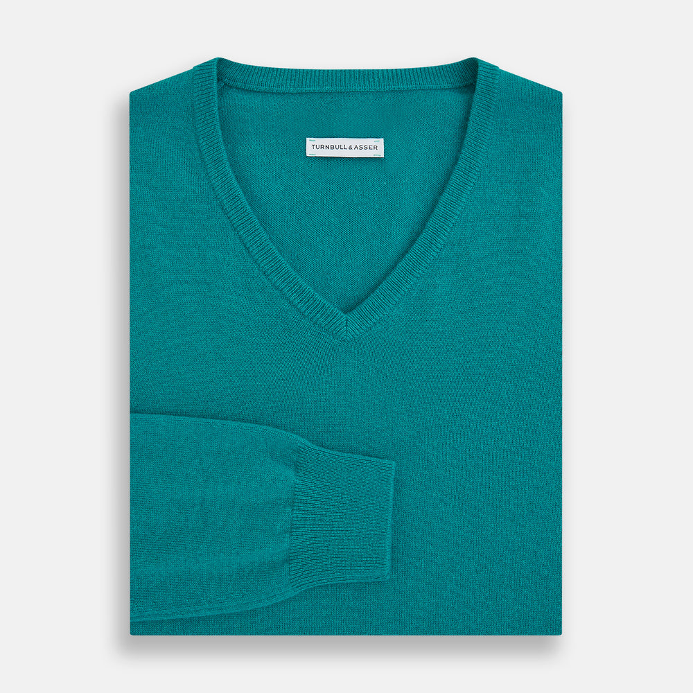 The Turnbull & Asser Turquoise Cashmere V-neck Jumper features long sleeves with ribbed cuffs and hem, displayed on a plain white background—a chic knitwear addition.