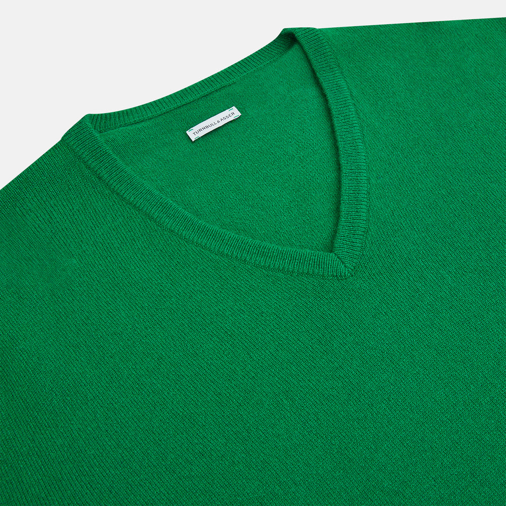 The Turnbull & Asser Grass Green Cashmere V-neck Jumper, with long sleeves, is displayed against a white background, highlighting its classic knitwear style.