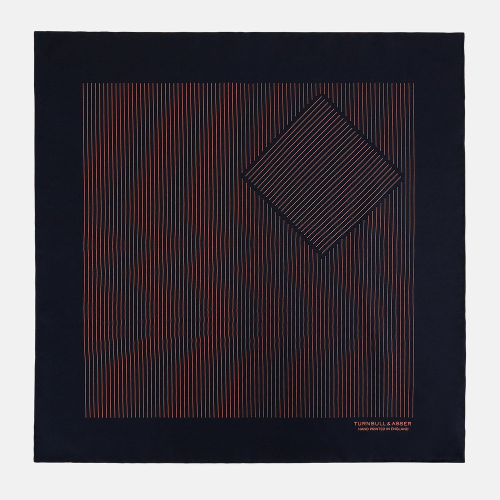 The Navy and Orange Stripe Silk Pocket Square by Turnbull & Asser is handmade in England from silk, featuring thin orange geometric stripes on navy and "Turnbull & Asser Hand Printed in England" printed in the corner.