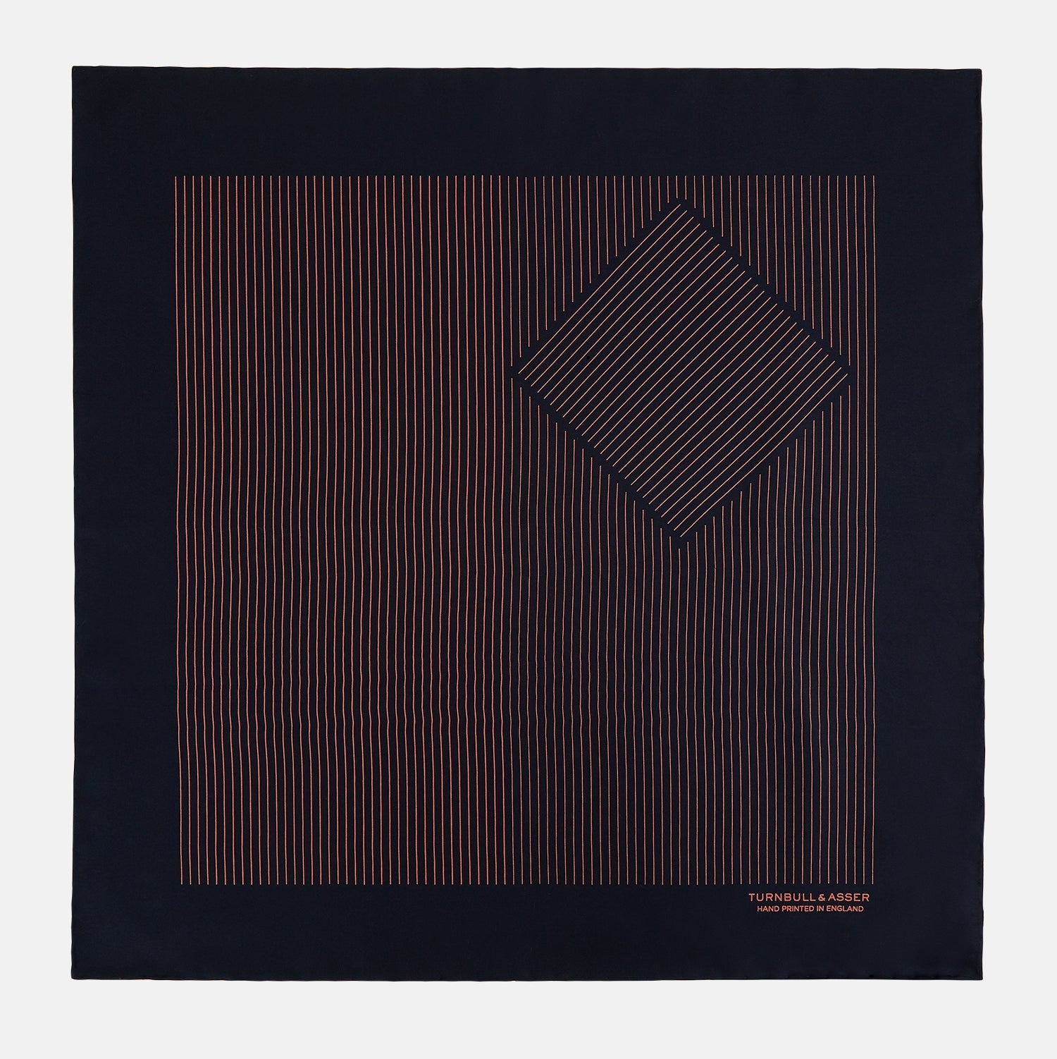 View 3 of product The Navy and Orange Stripe Silk Pocket Square by Turnbull & Asser is handmade in England from silk, featuring thin orange geometric stripes on navy and "Turnbull & Asser Hand Printed in England" printed in the corner.