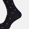 View 4 of product The Turnbull & Asser Midnight Patterned Mid-Length Sock features a ribbed cuff and a design of small white hexagons with red dots, shown here as a single sock on a plain white background.