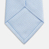 View 3 of product The HOUNDSTOOTH WHITE RIVER TIE by Turnbull & Asser features a light blue and white textured pattern, making it an essential accessory for elegant looks, shown beautifully rolled on a plain white background.