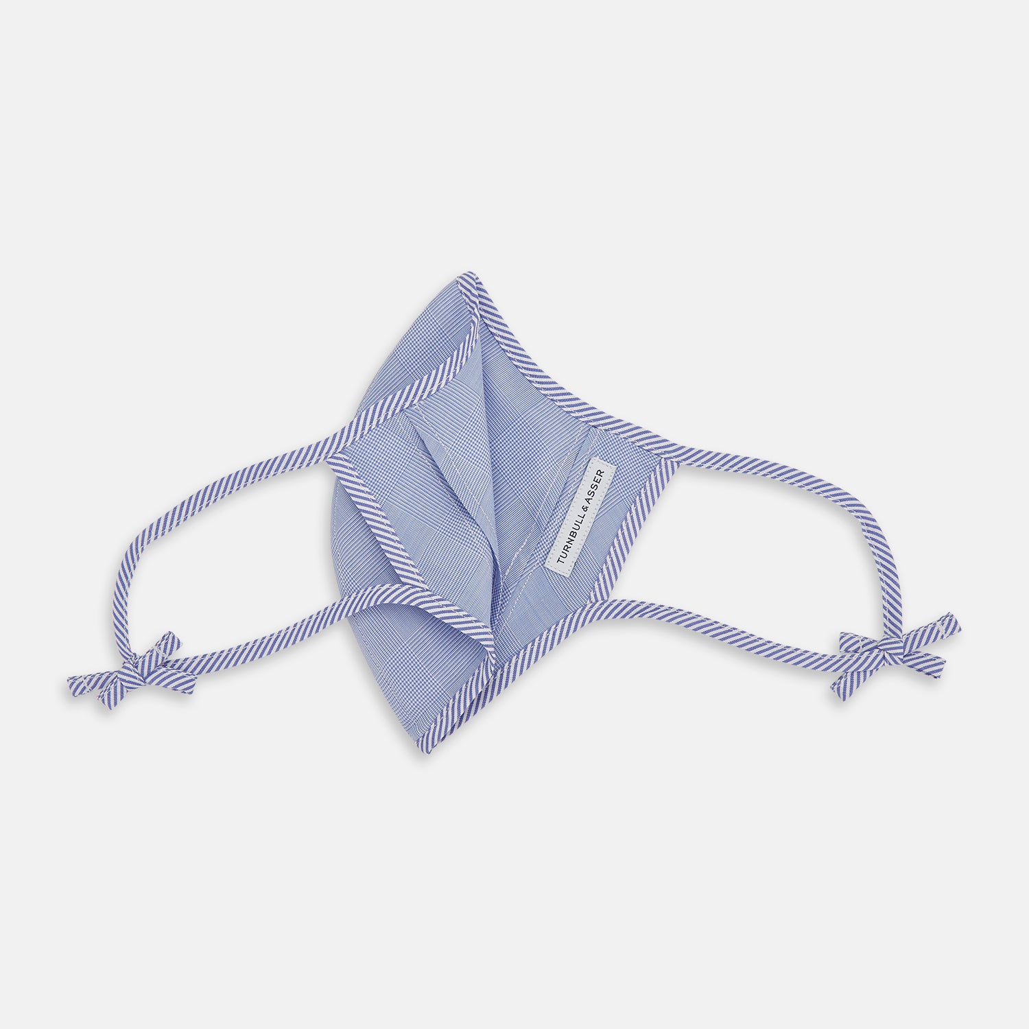View 5 of product The Turnbull & Asser Blue Fine Check Zephyr Cotton Commuter Mask features a light blue and white check pattern, adjustable side ties, and comes with 3 Viroformula™ filters. Shown on a plain white background.