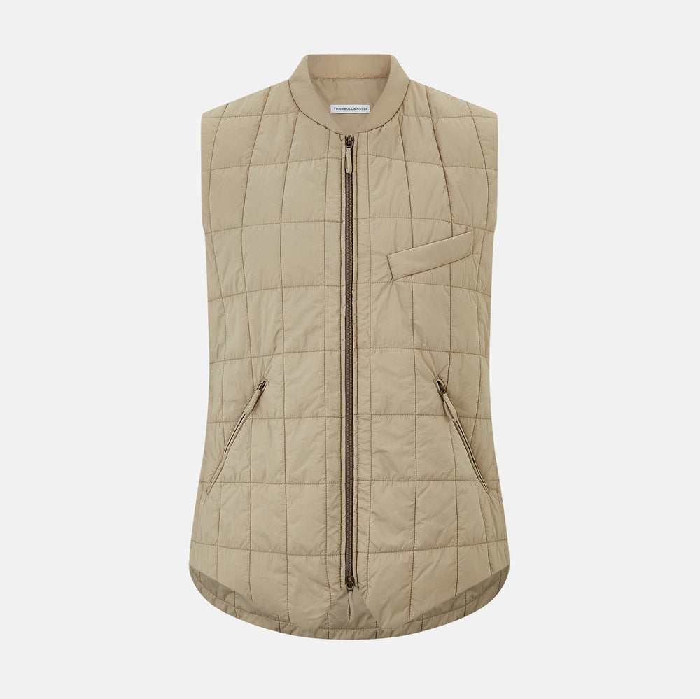 The Turnbull & Asser Sand Quilted Gilet is a beige, lightweight vest featuring a front zipper, two zippered side pockets, a chest pocket, and a rounded hem, shown against a white background.