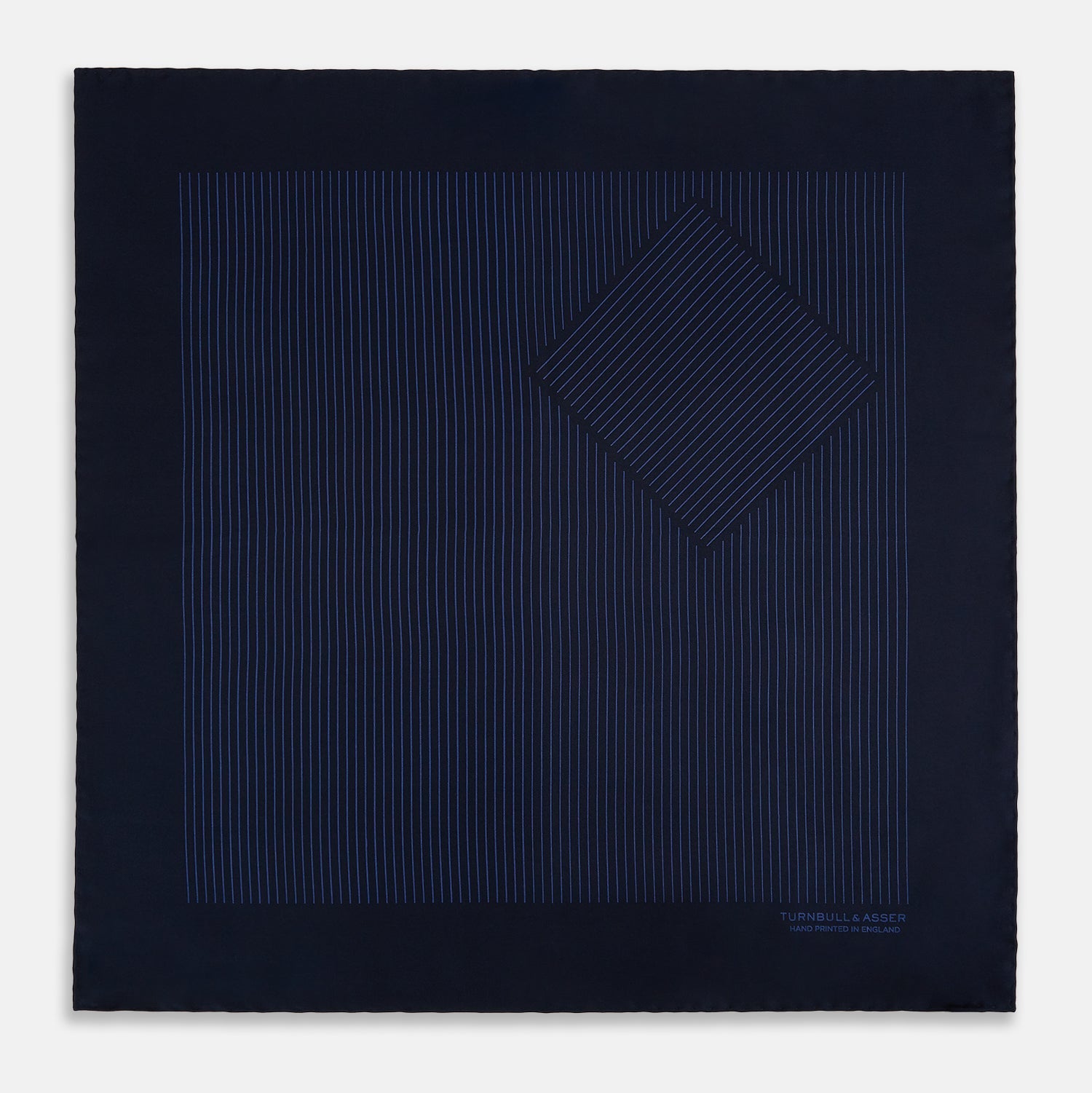 View 3 of product The Navy Stripe Silk Pocket Square by Turnbull & Asser features a dark navy silk with thin light blue stripes and hand-rolled edges, folded to reveal both sides and “TURNBULL & ASSER HAND PRINTED IN ENGLAND” in the corner.
