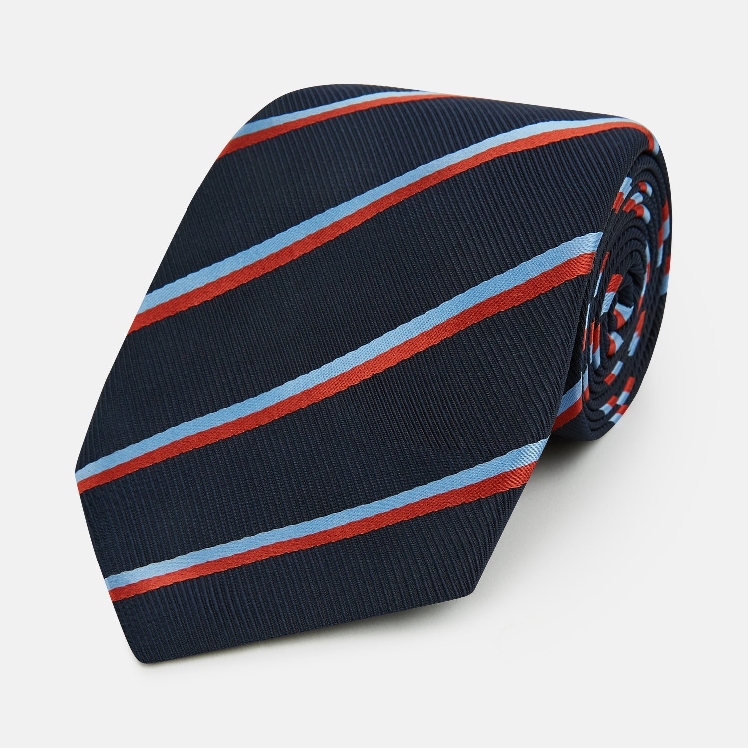 View 1 of product The Turnbull & Asser Red And Blue Stripe Silk Blend Tie, rolled on a white background, features refined diagonal accents—an elegant formal accessory.