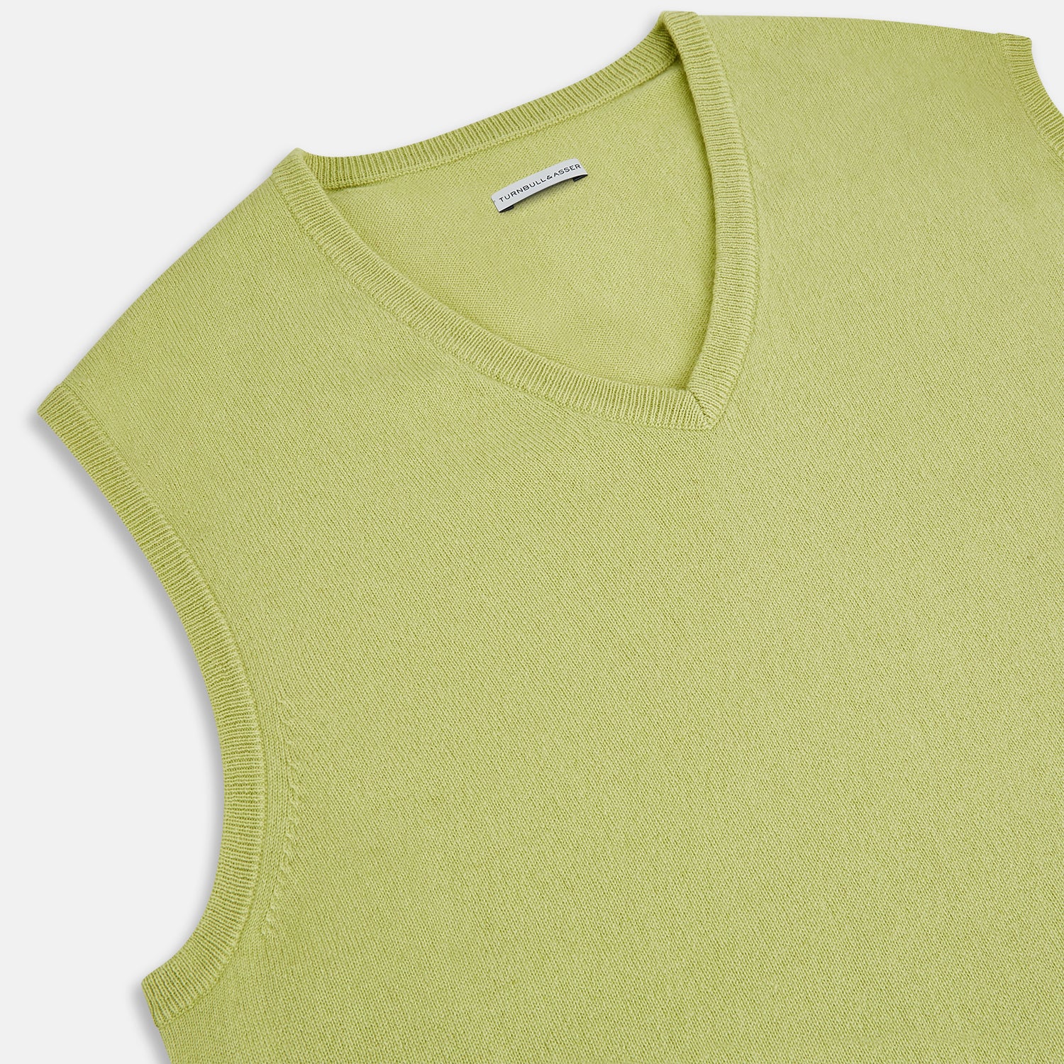 View 2 of product Turnbull & Asser’s Melon Green V-neck Cashmere Vest is shown on a plain white background. This sleeveless men’s jumper features ribbed neckline, armholes, and hem for subtle detail.