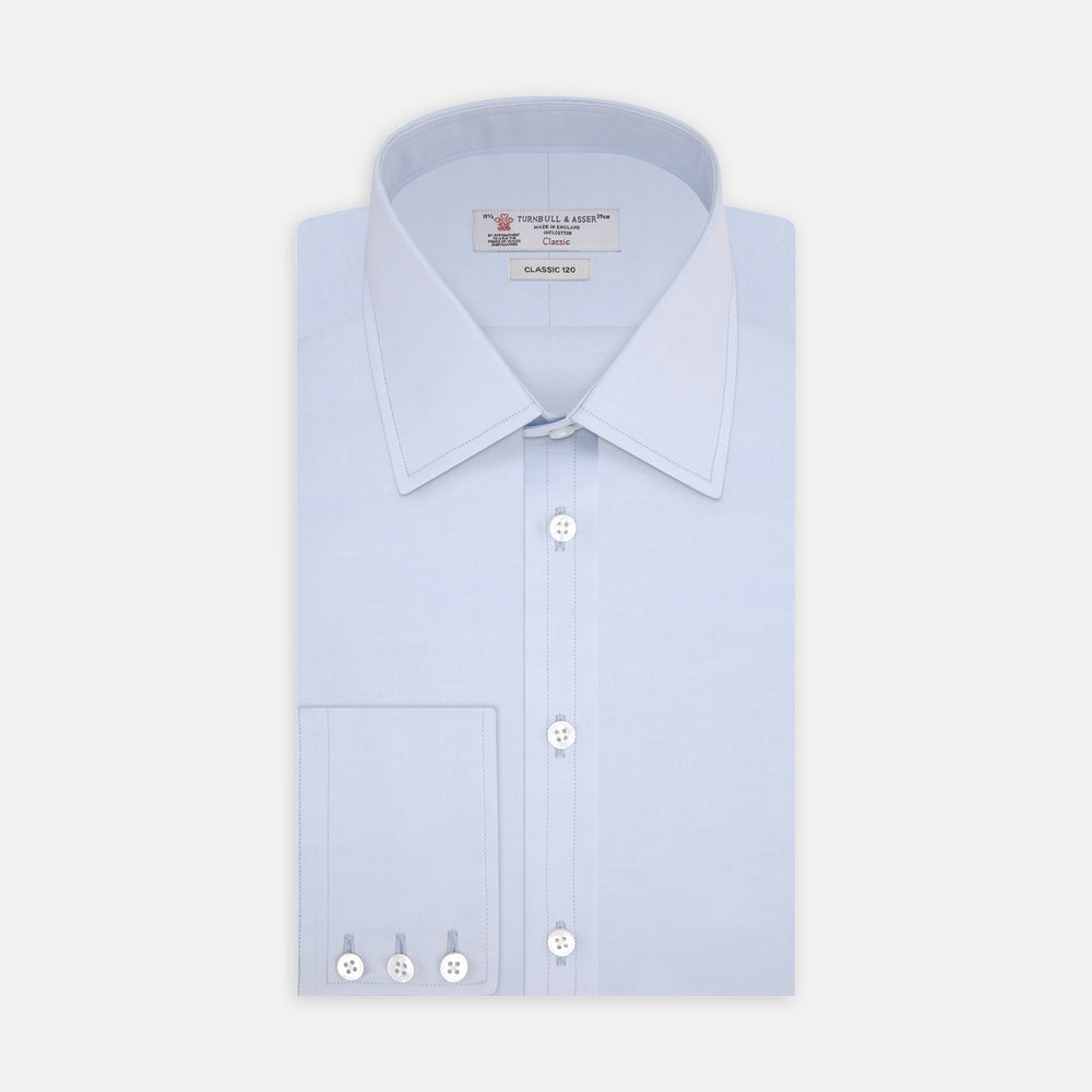 The Turnbull & Asser Two-Fold 120 Light Blue Shirt features a T&A collar, 3-button cuffs, white buttons, front pocket, and inner collar label. It is displayed neatly folded on a plain white background.