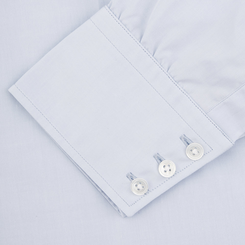 The Turnbull & Asser Two-Fold 120 Light Blue Shirt features a T&A collar, 3-button cuffs, white buttons, front pocket, and inner collar label. It is displayed neatly folded on a plain white background.