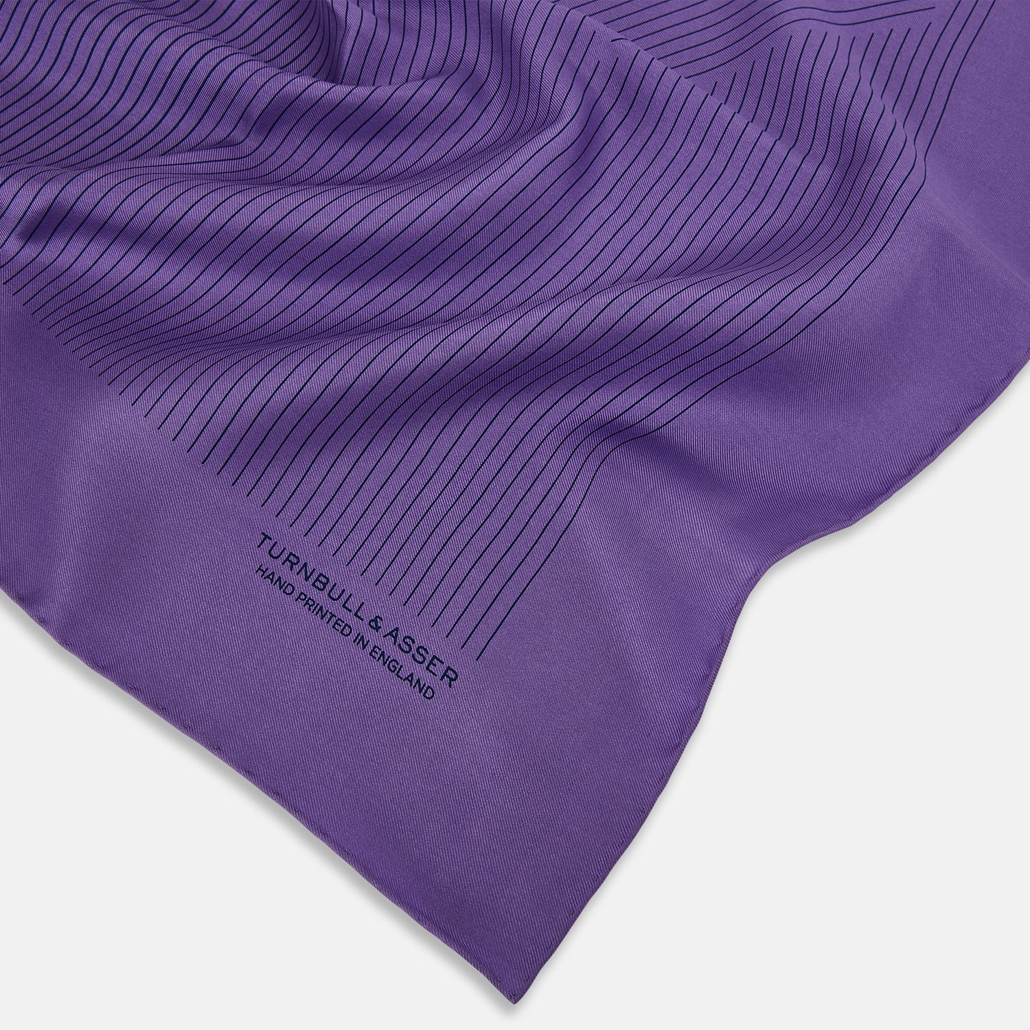 View 2 of product The Purple Stripe Silk Pocket Square by Turnbull & Asser features thin black lines on purple silk—a sophisticated blazer accessory hand printed in England, showcasing classic British craftsmanship.