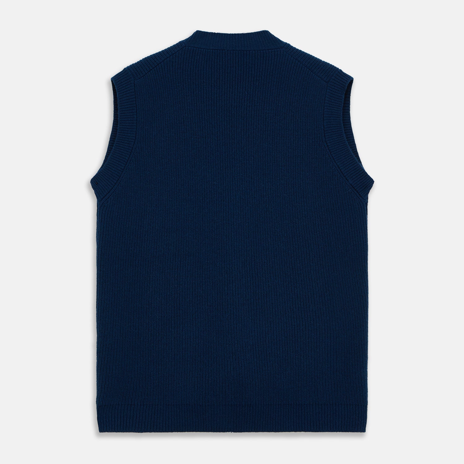 View 5 of product A man with a shaved head wears a Turnbull & Asser Navy Sleeveless Cashmere Cardigan over a white dress shirt with rolled-up sleeves and dark trousers, standing against a plain light gray background.