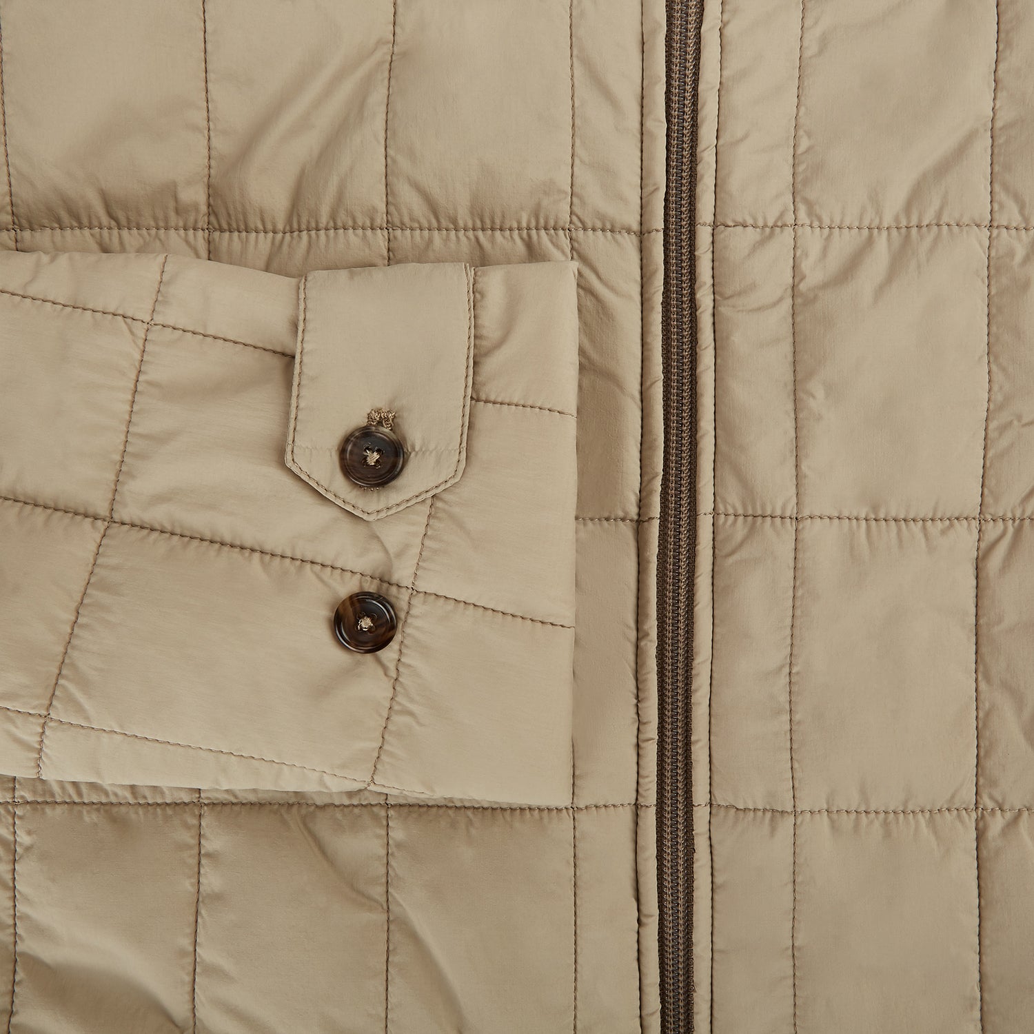 View 4 of product The Battersea Sand Quilted Jacket by Turnbull & Asser is a light beige men's jacket with a front zipper, pointed collar, zippered side pockets, chest pocket, and buttoned cuffs, shown on a plain white background.