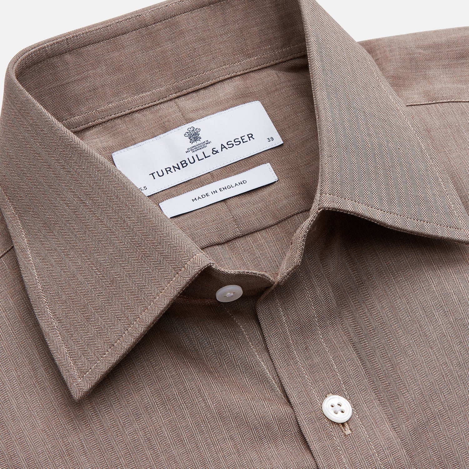 View 4 of product The Turnbull & Asser Camel Cotton Melange Regular Fit Mayfair Shirt features long sleeves, a classic T&A collar, white buttons, and buttoned cuffs in light brown cotton melange, displayed flat on a white background.