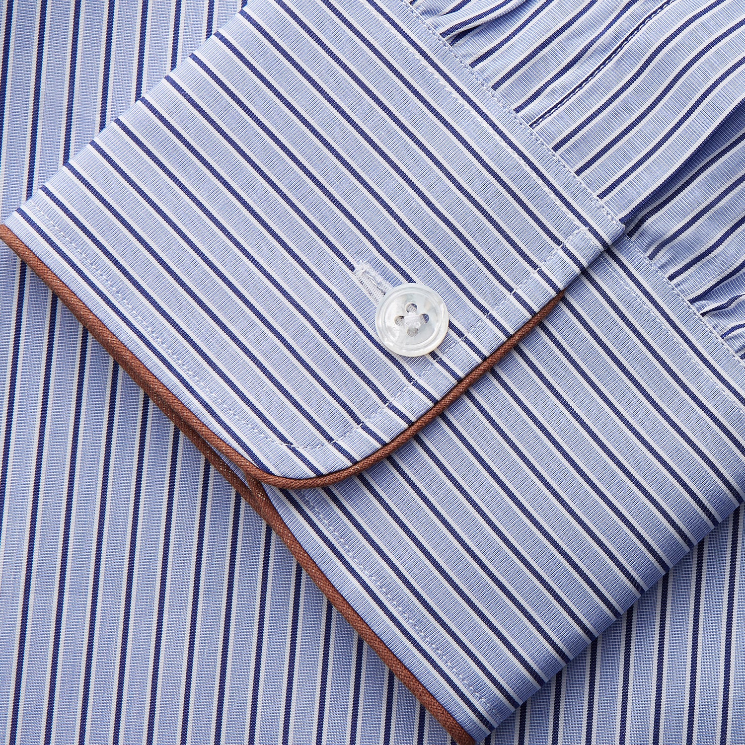 View 3 of product The Blue and Navy Halo Stripe Cotton Sussex Nightshirt by Turnbull & Asser features long sleeves, a collar, button-down front, chest pocket, curved hem, and brown piping for a classic luxury sleepwear style.