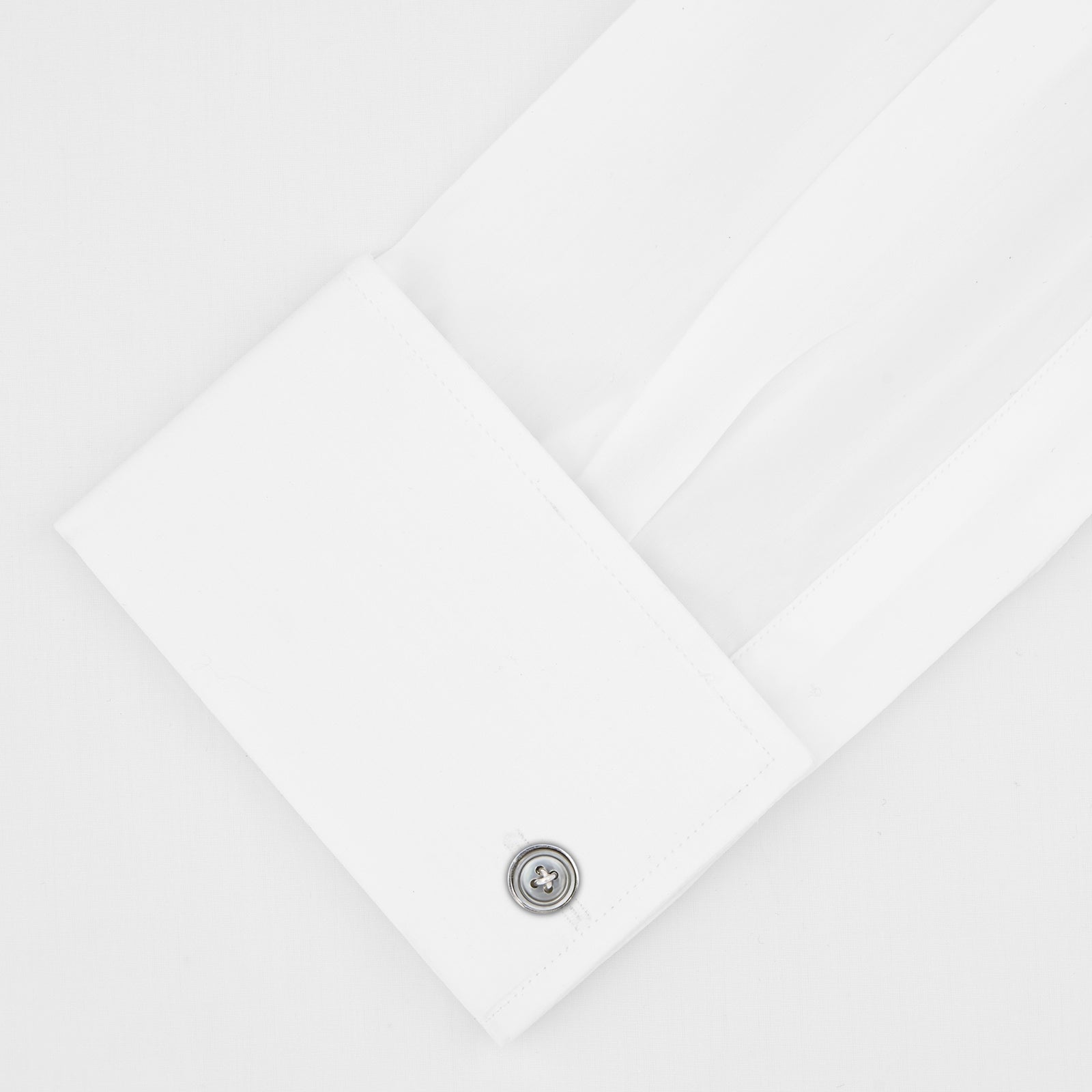 View 2 of product The Turnbull & Asser Tailored Fit Two-Fold 120 White Cotton Shirt features a Kent collar, double cuffs, and button-down front, displayed neatly folded against a light blue background.