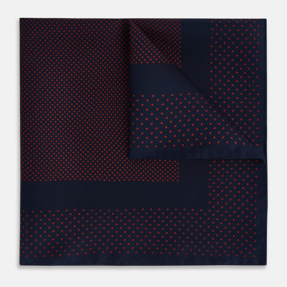 The Turnbull & Asser Navy and Red Dot Silk Pocket Square features a dark navy blue base with small red polka dots on the border and inner pattern, all handmade and neatly folded.