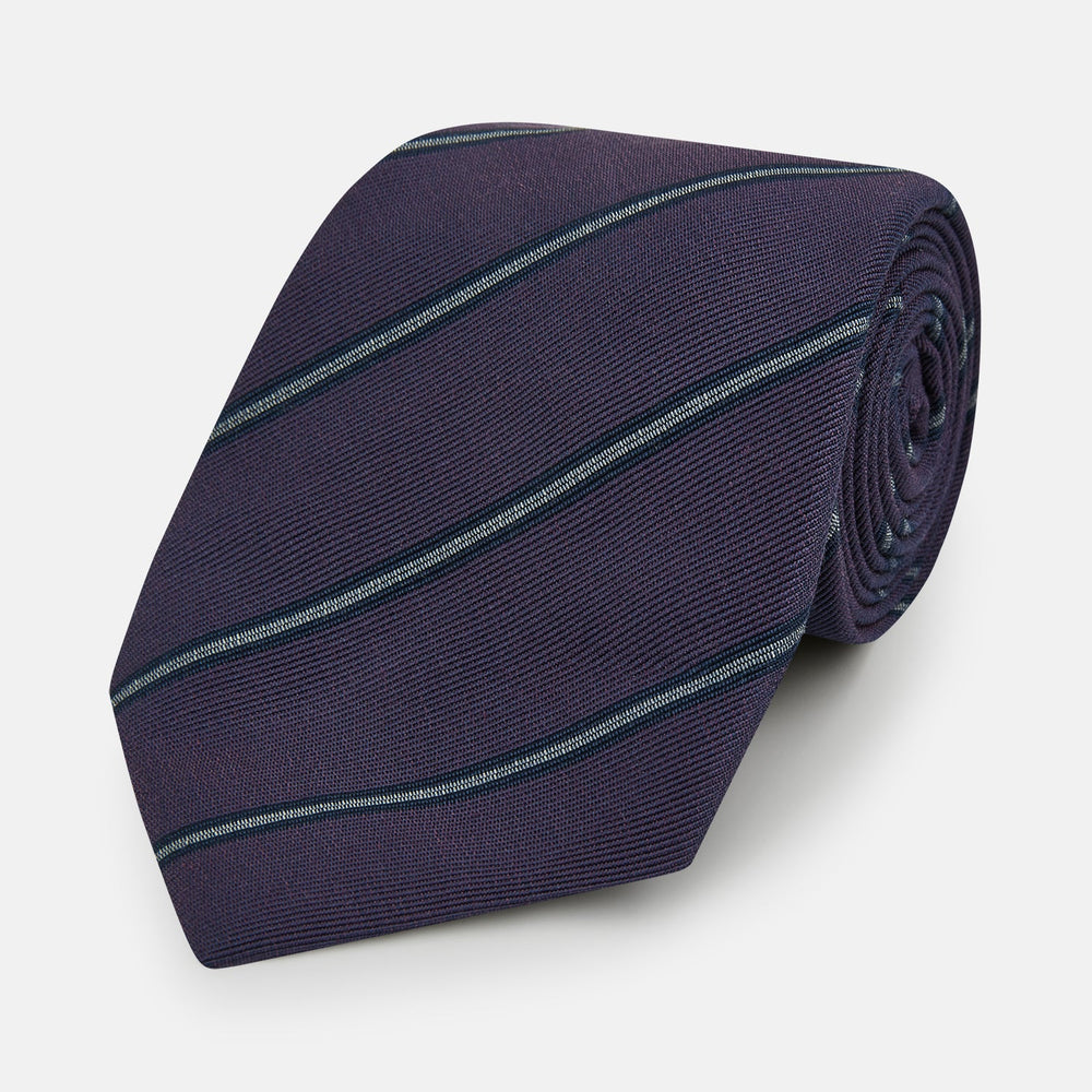 The Turnbull & Asser Purple Multi Stripe Silk Blend Tie, featuring thin light blue diagonal stripes, is neatly rolled on a white background.