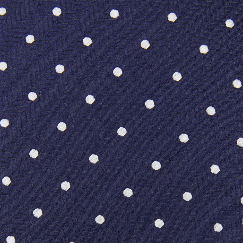 The Turnbull & Asser Navy and White Spot Woven Herringbone Silk Tie, shown rolled-up on a white background, features a classic polka dot pattern—an elegant accessory for refined wardrobes.