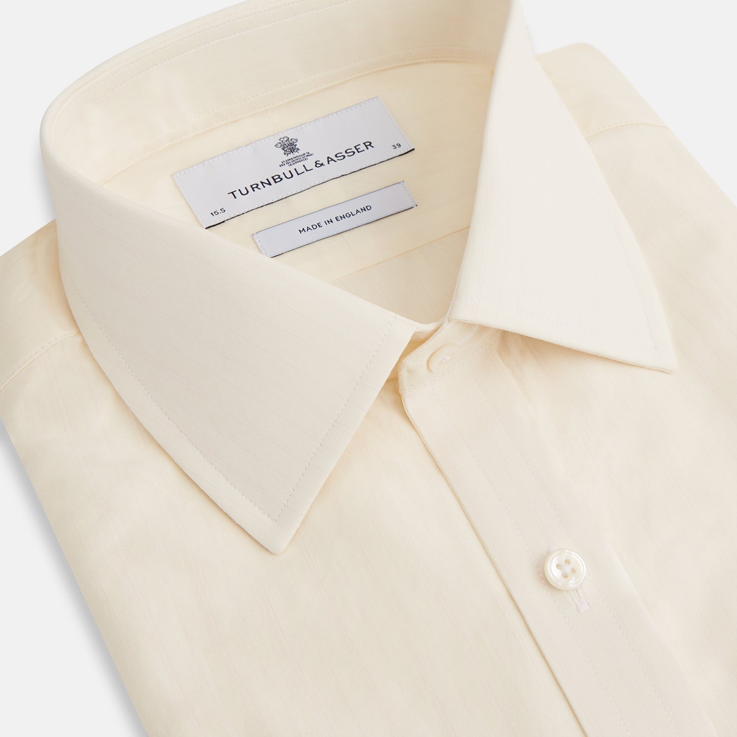 View 2 of product The Cream Fine Pencil Stripe Mayfair Shirt by Turnbull & Asser features long sleeves, a pointed collar, and buttoned cuffs. Crafted from breathable cotton with fine pencil stripes, it is shown laid flat on a white background.