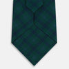View 3 of product The Turnbull & Asser Forest Melange Tartan Plaid Silk Tie features a classic green and blue plaid design, rolled up and displayed on a plain light background—reflecting timeless Scottish heritage.