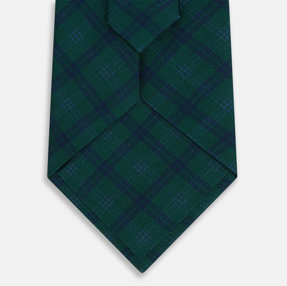 The Turnbull & Asser Forest Melange Tartan Plaid Silk Tie features a classic green and blue plaid design, rolled up and displayed on a plain light background—reflecting timeless Scottish heritage.