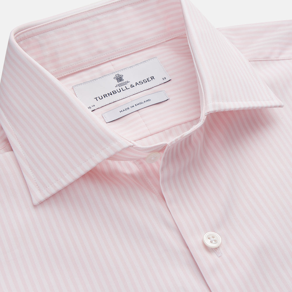 The Turnbull & Asser White and Pink Wide Stripe Shirt with Double Cuffs features a minimalist design, with bold vertical stripes and long sleeves, shown laid flat against a white background.