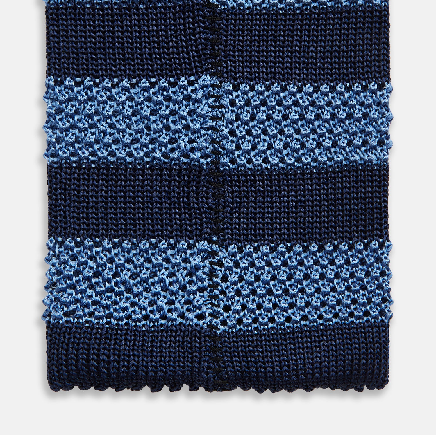 View 4 of product The Turnbull & Asser Navy and Blue Square tipped knitted tie features horizontal stripes and a rolled-up silk design, elegantly displayed on a plain white background.