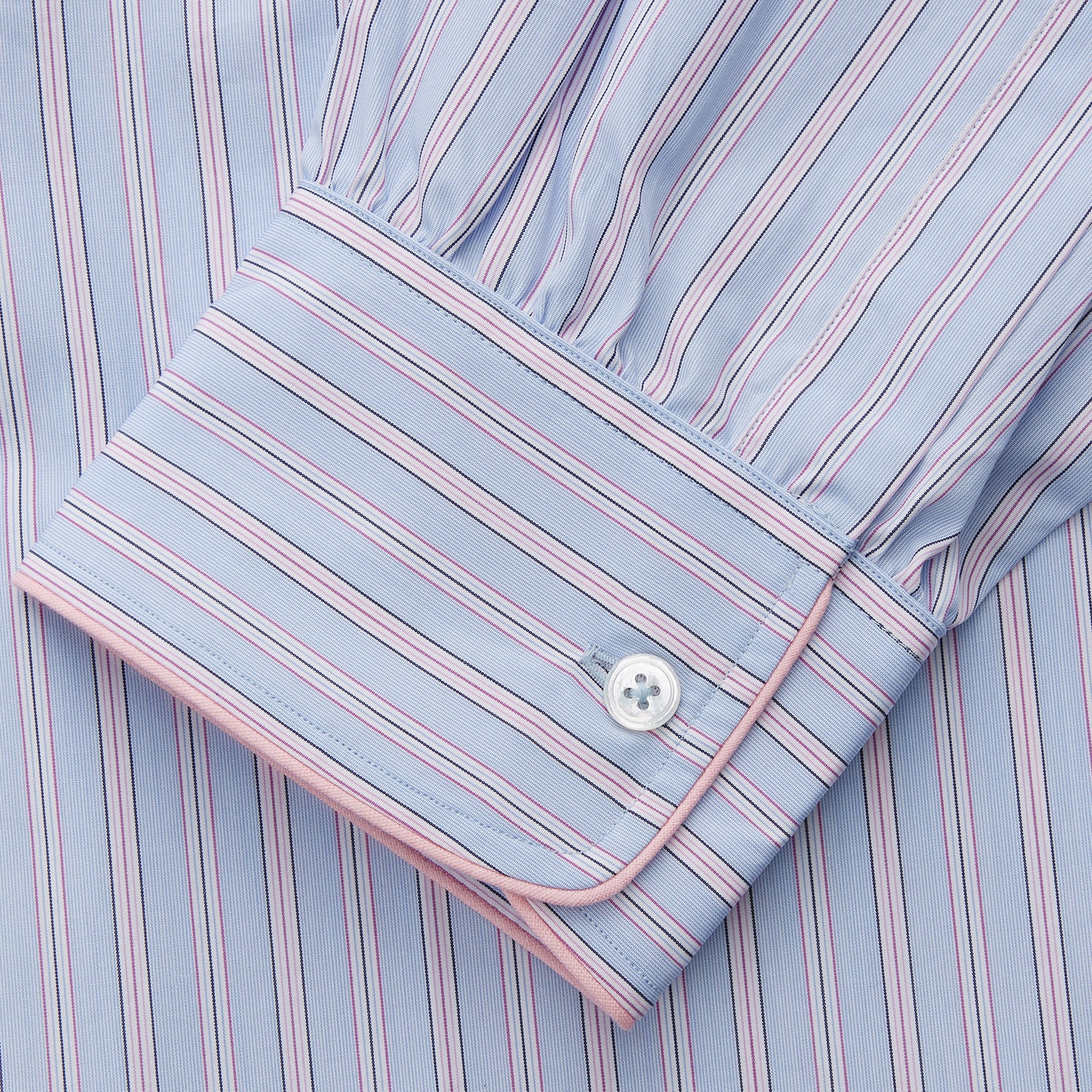 View 3 of product The Blue and Pink Stripe Poplin Cotton Nightshirt by Turnbull & Asser features long sleeves, a collar, front buttons, chest pocket, rounded hem, and light blue fabric with white, pink, and yellow vertical stripes.